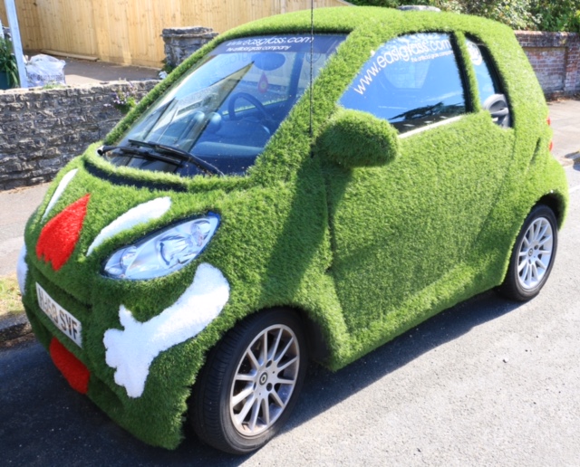 A car covered in artificial grass to advertise a company.